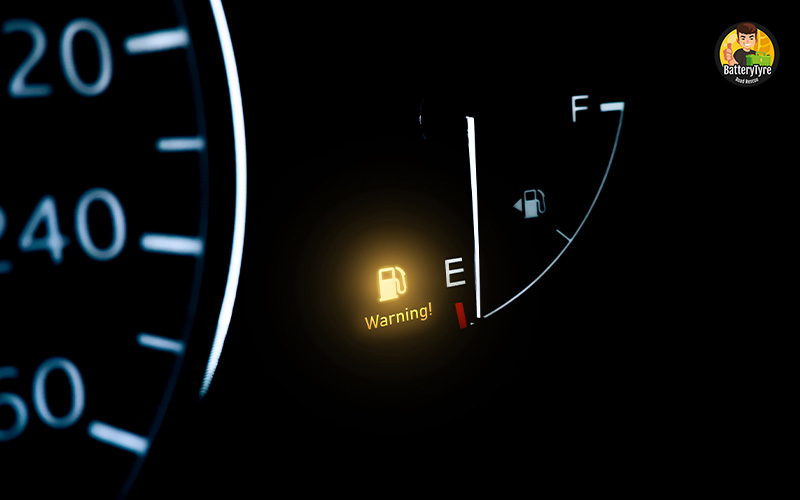 Car fuel gauge showing empty with warning light.