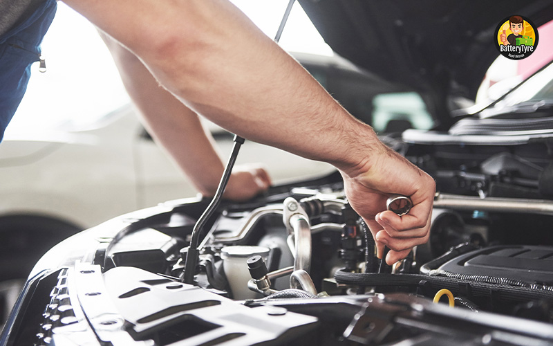 Mechanic inspecting car engine to fix starting issue.