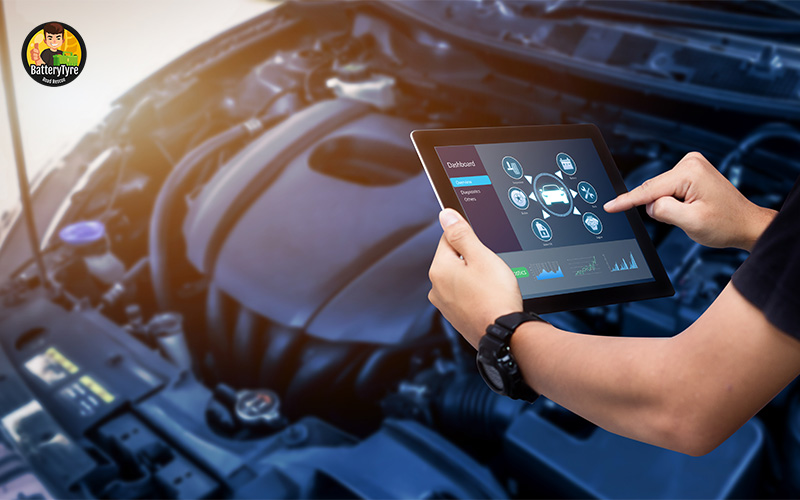 Technician performing car battery diagnostics with a tablet.
